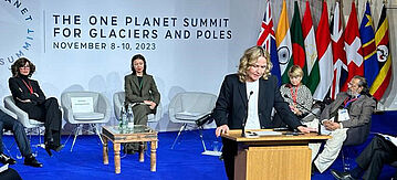 Steffi Lemke an einem Rednerpult mit Menschen auf Stühlen und europäischen Flaggen hinter ihr