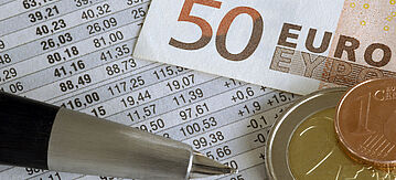 Geldschein, Münzen und ein Stift liegen auf Abrechnungsdokument