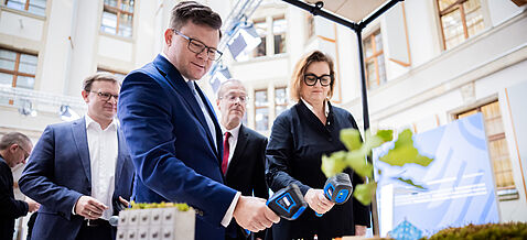 Carsten Schneider und Ina Czyborra betrachten ein Modell "Hitzestadt", das die Auswirkungen von extremer Hitze auf unterschiedliche Teile der Stadt zeigt.