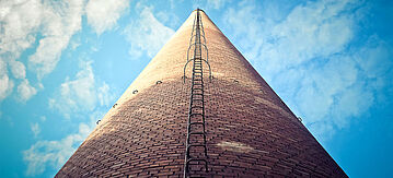 Blick von unten nach oben einen Schornstein einer Industrieanlage entlang