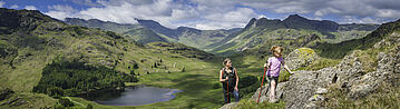 Aktive Mutter und Tochter wandern in einer idyllischen Landschaft.