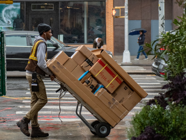 Ein Paketbote liefert Pakete auf einem Transportwagen
