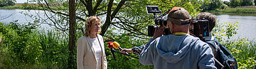 Steffi lemke wird an der Oder von der Presse interviewt.
