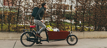 Mann auf einem Lastenfahrrad mit Einkauf